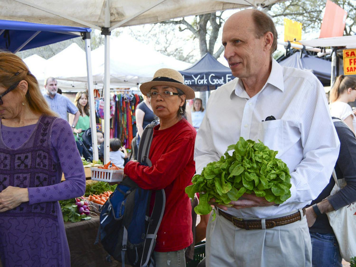 A Gainesville resident for almost 60 years, Austin Gregg waits in line to purchase a pair of oak leaf lettuces at the Union Street Farmers Market. Gregg said he was glad the farmers market was back at Bo Diddley because he felt the space had more character than Lot 10.