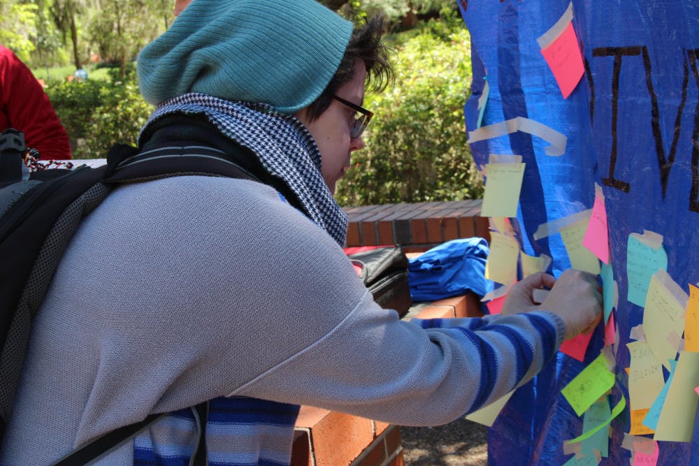 Teresa Sellos, a UF computer science fifth-year, tapes a Post-It note to a Student Government’s banner that reads “What makes you diverse?” on Monday on Turlington Plaza. The banner is part of a weeklong series of events hosted by Student Government called Diversity Week.