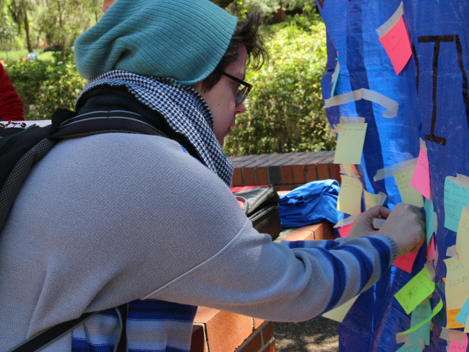 Teresa Sellos, a UF computer science fifth-year, tapes a Post-It note to a Student Government’s banner that reads “What makes you diverse?” on Monday on Turlington Plaza. The banner is part of a weeklong series of events hosted by Student Government called Diversity Week.