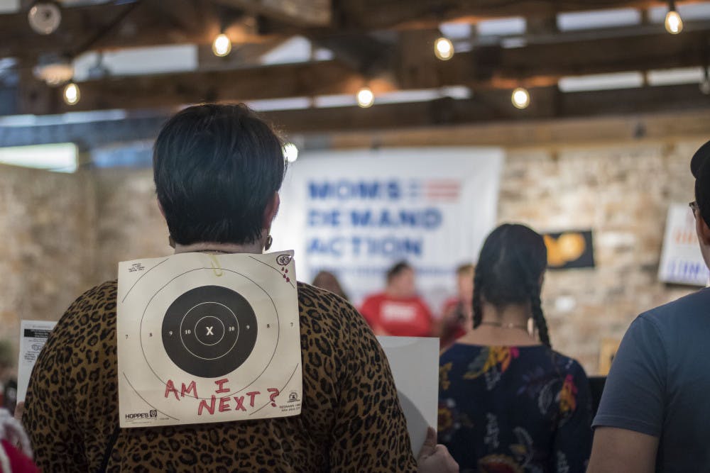 Several protestors stand holding signs Saturday afternoon during the Recess Rally. Many of the activists wore targets on their backs blaming the NRA and lawmakers for recent gun deaths in the United States.