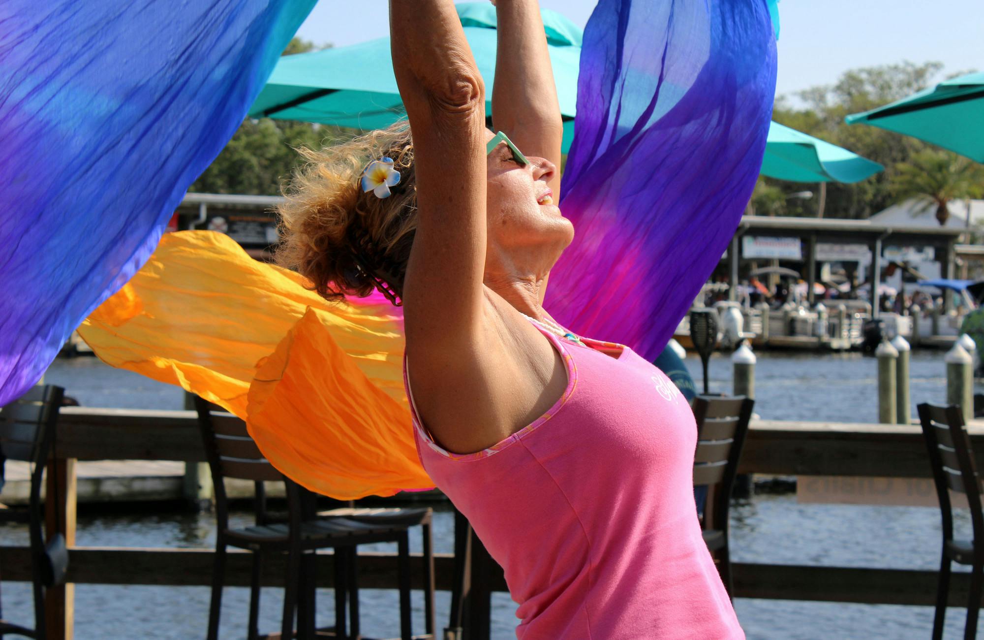 Elaine Hargrove, a 63-year-old Chiefland, Florida, resident, dances with colorful scarves at Crump’s Landing restaurant in Homosassa, Fla., on Sunday, April 16, 2023.