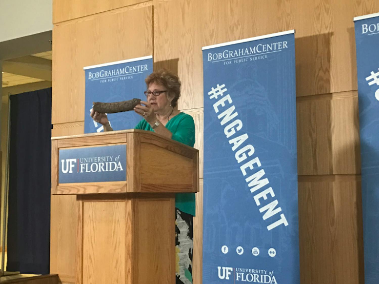 Martha Peterson Shogi holding a package shaped like a log, also known as a dead drop, that the CIA used to deliver materials to a Soviet diplomat who sent secret information to the CIA.