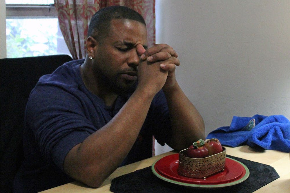 Michael Powers, 31, sits at his dining table where he is about to eat a baked chicken dinner for himself and his three sons. He lives in East Gainesville public housing, but dreams of moving to Savannah, Georgia.