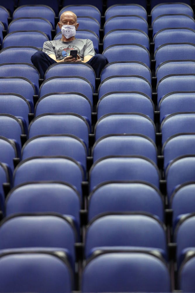 Mike Lemcke, from Richmond, Va., sits in an empty Greensboro Coliseum after the NCAA college basketball games were cancelled at the Atlantic Coast Conference tournament in Greensboro, N.C., Thursday, March 12, 2020. The biggest conferences in college sports all canceled their basketball tournaments because of the new coronavirus, seemingly putting the NCAA Tournament in doubt. (AP Photo/Ben McKeown)