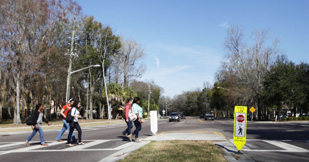 <p>Pedestrians cross Southwest 62nd Street on Wednesday afternoon. Gainesville Police issued more than 120 traffic citations near the crosswalk during the past two days, a majority of which went to drivers.</p>