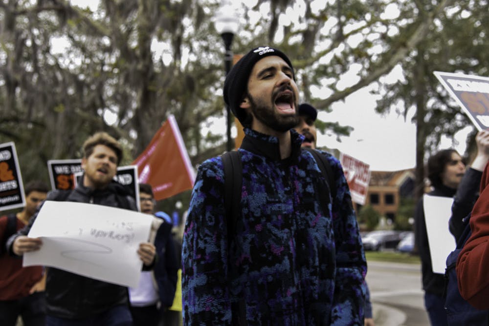 Anton Kernohan, a 20-year-old UF political science and sustainability sophomore, chants as protesters walk from Plaza of the Americas to the front entrance of Tigert Hall on Friday. 