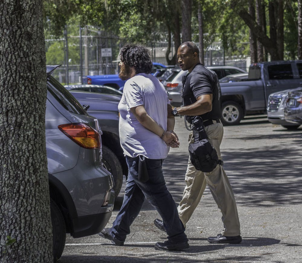 Jordan Mazurek, 28, is detained by an ACSO deputy on Monday after taking a construction cone. He was arrested for larceny, a second-degree misdemeanor.