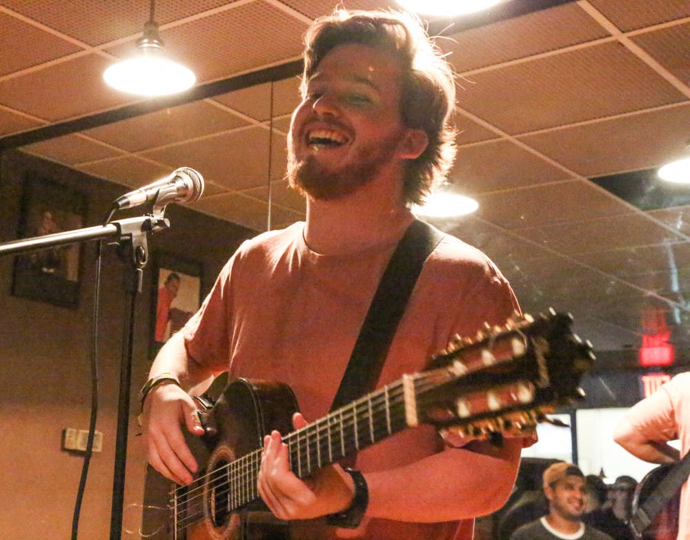 Simon Grossman, a 21-year-old UF telecommunication senior, performs “Te Invito”, a song from his upcoming album at Omi’s Tavern during the open-mic night, which was hosted by Vensa. People donated food and medical supplies to send to Venezuela. See the photo story on page nine.