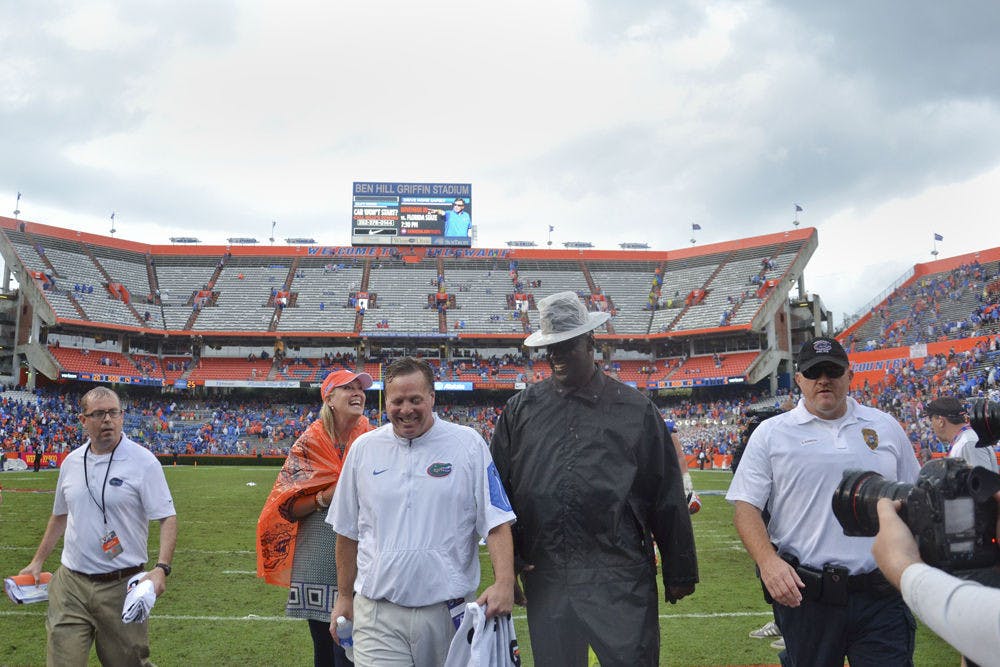 <p>A drenched UF football coach Jim McElwain (center) walks off the field at Ben Hill Griffin Stadium following Florida's 20-14 overtime win against Florida Atlantic on Nov. 21, 2015, at Ben Hill Griffin Stadium.</p>