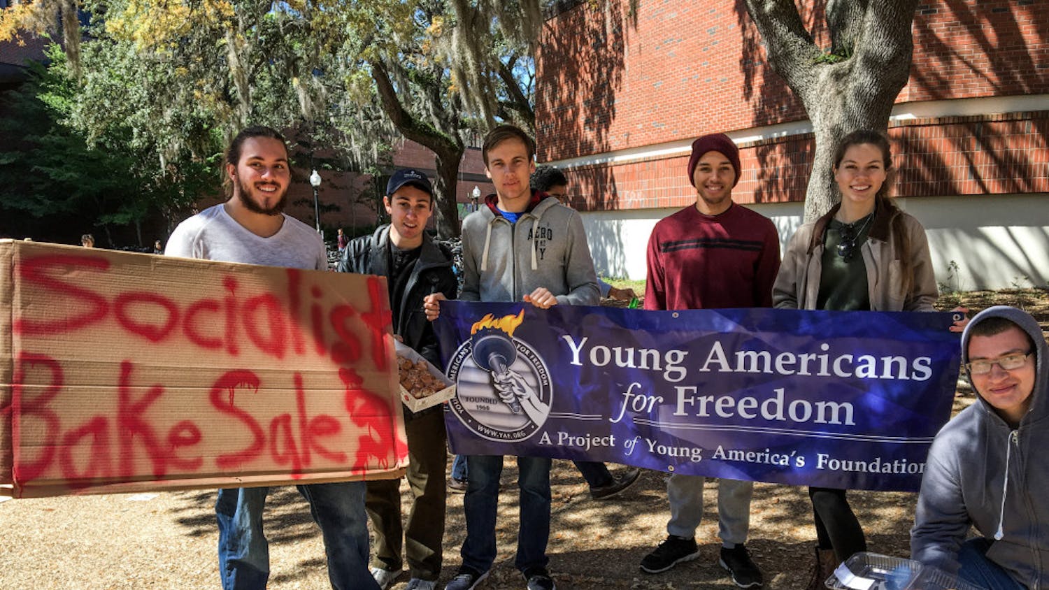 Members of UF’s Young Americans for Freedom pose in front of a sign advertising their socialist bake sale on Turlington Plaza on Wednesday. Members of the student organization sold cookies and doughnuts, giving some away, to point out the issues with socialism.