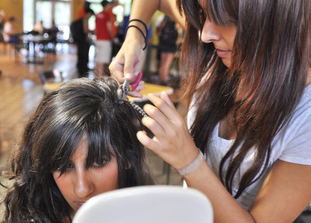 Raquel Farinas secures one of her pieces into third-year hospitality major Aleen Touma's hair.