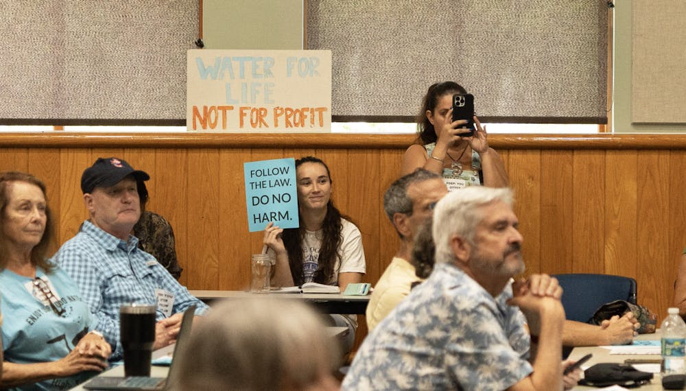 Environmental activist groups hold up signs supporting the protection of the springs at Alachua County Library on Monday, Aug. 28, 2023.