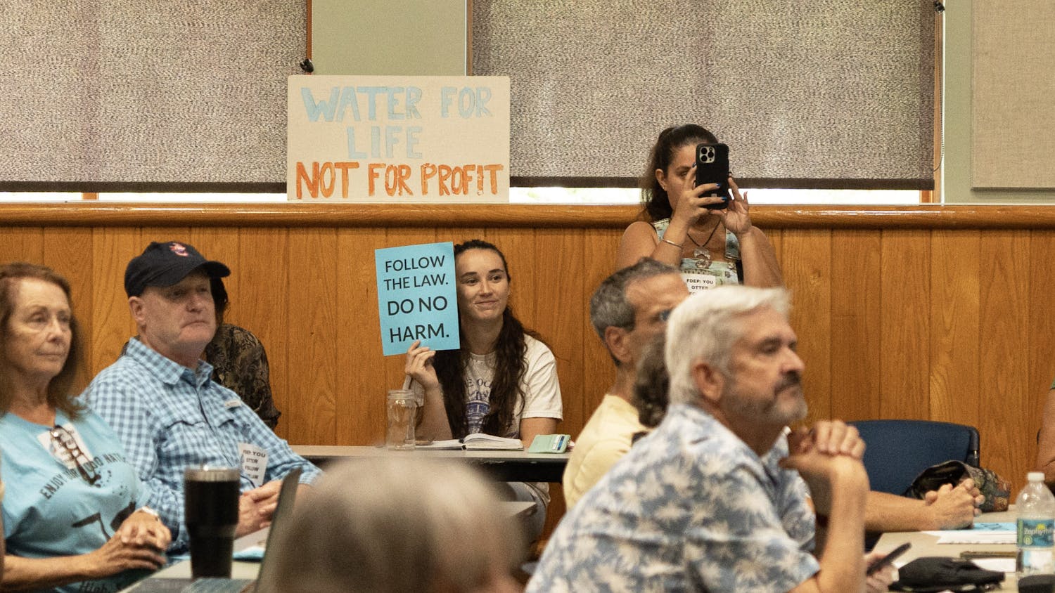 Environmental activist groups hold up signs supporting the protection of the springs at Alachua County Library on Monday, Aug. 28, 2023.