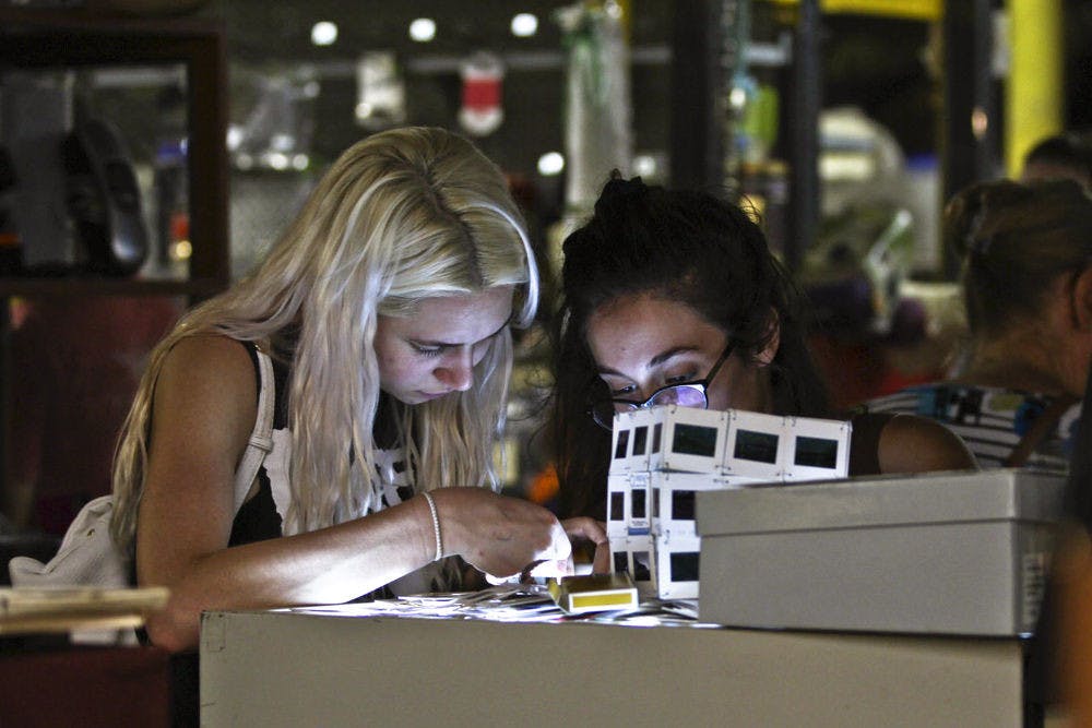 <p>Finance major Peyton Hilford (left) looks at film negatives and slides with 20-year-old UF graphic design junior Maitane Romagosa inside the Repurpose Project during the Fall Trash Festival. “I love trash,” said Hilford, a 20-year-old UF junior.</p>