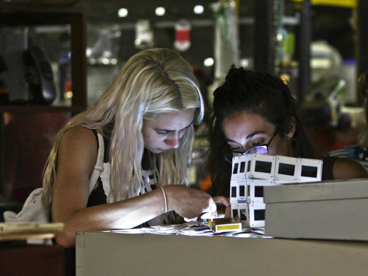 Finance major Peyton Hilford (left) looks at film negatives and slides with 20-year-old UF graphic design junior Maitane Romagosa inside the Repurpose Project during the Fall Trash Festival. “I love trash,” said Hilford, a 20-year-old UF junior.