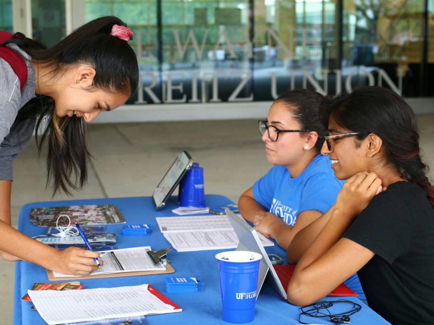 Bob Graham Center for Public Service student fellows Priya Amilineni (right) and Dalia Figueredo (center) register a student to vote during the July 19 voter registration event in coordination with the Alachua County Supervisor of Elections. 