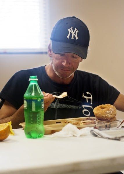 Bob Adams eats at the St. Francis House, 413 S. Main St., on Monday morning. New regulations require people using any service at the shelter and soup kitchen to obtain police clearance.