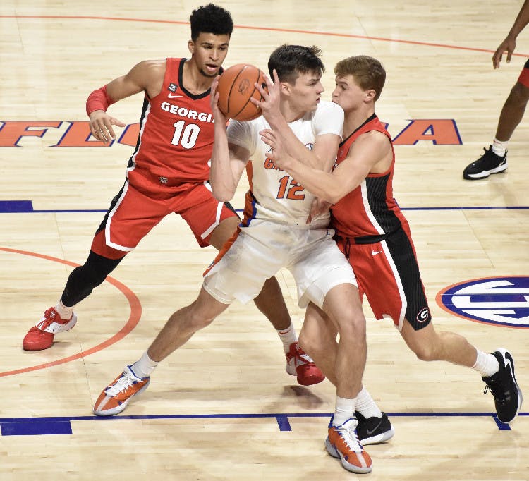 Junior Colin Castleton battles in the post against two Georgia defenders Saturday. Castleton led the Gators with 14 points in a winning effort