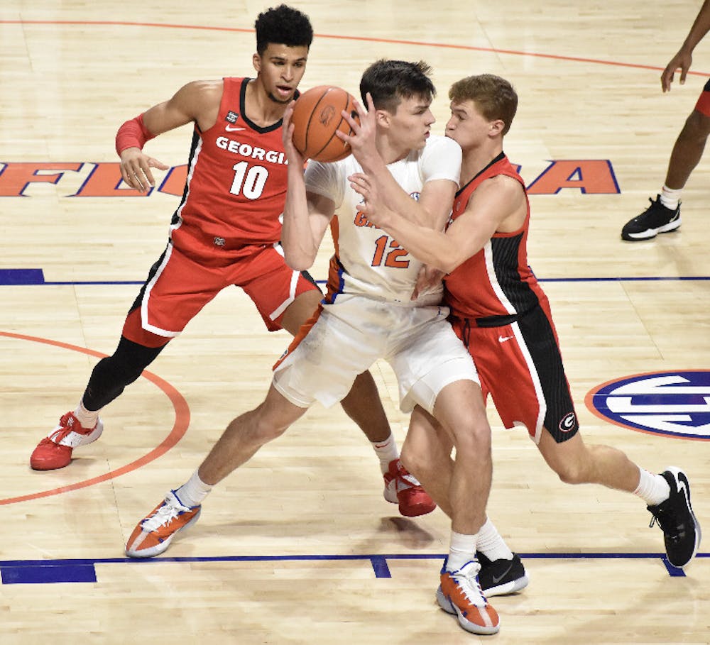 <p>Junior Colin Castleton battles in the post against two Georgia defenders Saturday. Castleton led the Gators with 14 points in a winning effort</p>