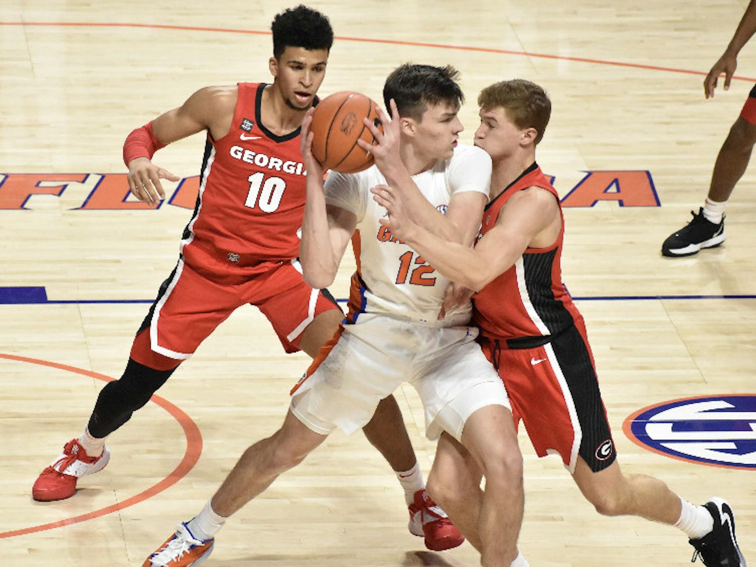 Junior Colin Castleton battles in the post against two Georgia defenders Saturday. Castleton led the Gators with 14 points in a winning effort
