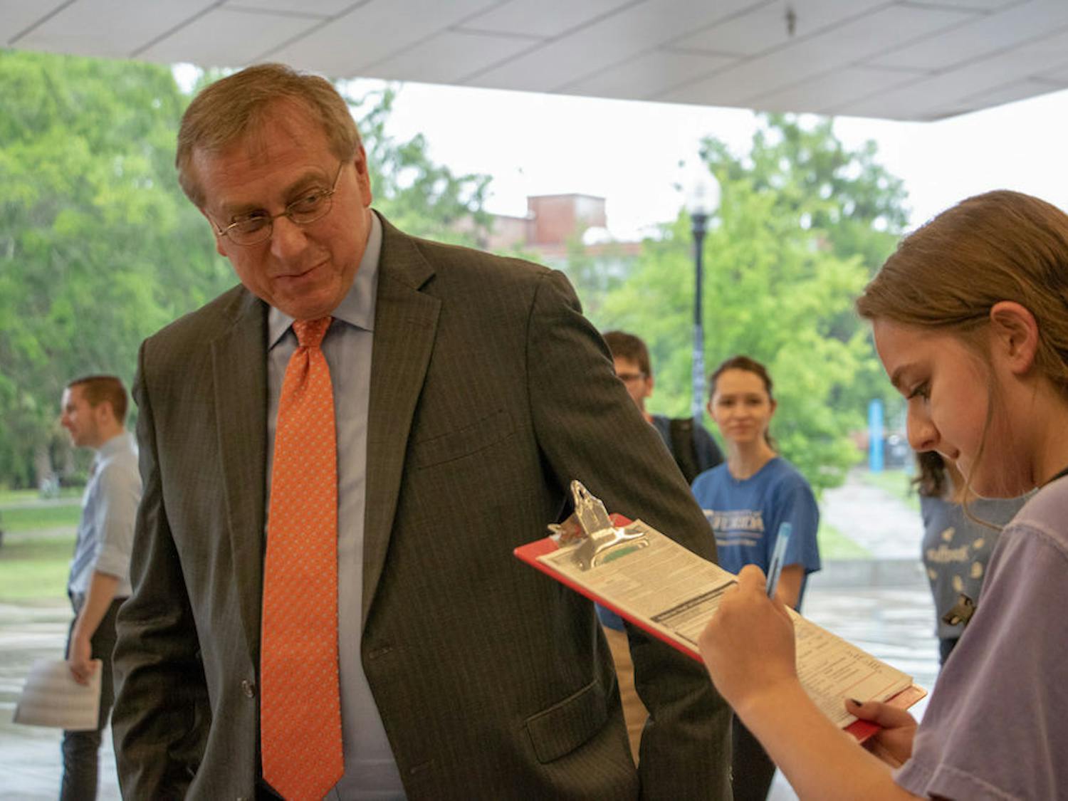From left: UF President Kent Fuchs assists Natalie Evelev, an 18-year-old UF biomedical engineering freshman, with registering to vote at the Voter Registration Drive with UF President Kent Fuchs and Alachua County Supervisor of Elections Kim Barton outside the Reitz Union on Monday afternoon. Evelev said she wanted to register to vote.