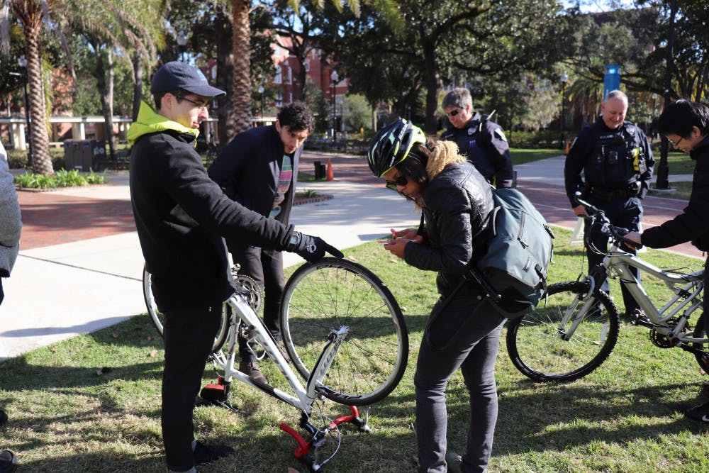 Seth Wood, 23, and Lian Plass, 24, both first-year UF urban and regional planning graduate students, examine Plass’ bike on the Plaza of the Americas Nov. 28 at a “Bike to Campus Day”, that rewarded bicyclists with free food. 