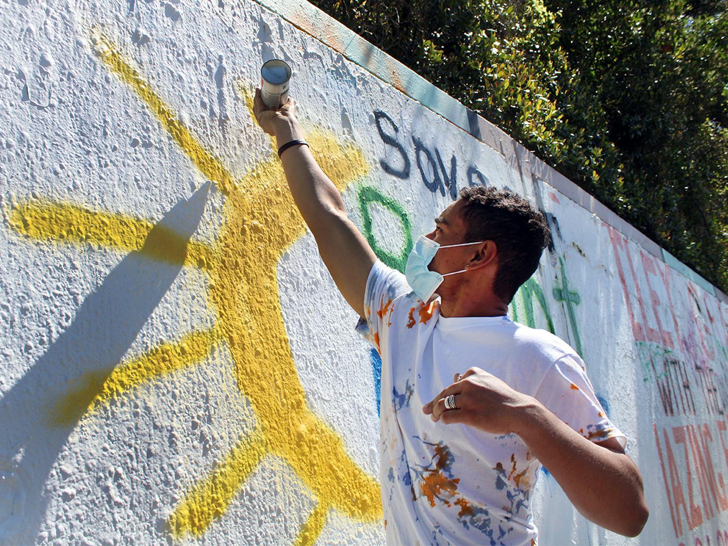 Oscar Santiago, 18, a political science freshman, finishes spray painting a sun on a mural that reads "Save our Bright Futures" on Sunday, March 7, 2021. The mural was painted in response to Senate Bill 86, which would limit some students’ access to state funding, including the Bright Futures scholarship.