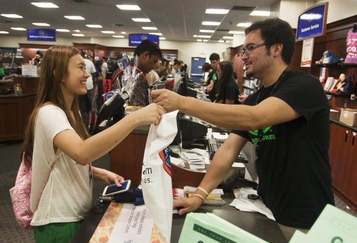 Freshman Truc Nguyen, an 18-year-old nutrition major, purchases books for her first semester from bookstore associate David Martinez, 25, Tuesday afternoon