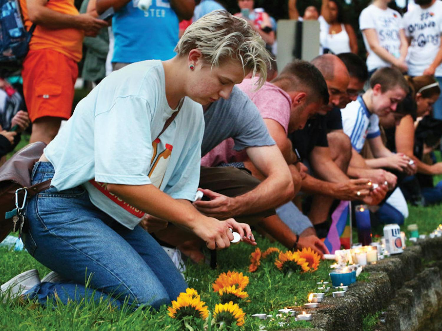 Sarah Schumaker, 23, leads a group of mourning Orlando residents and visitors in lighting candles at the vigil held at Lake Eola Park on Sunday.