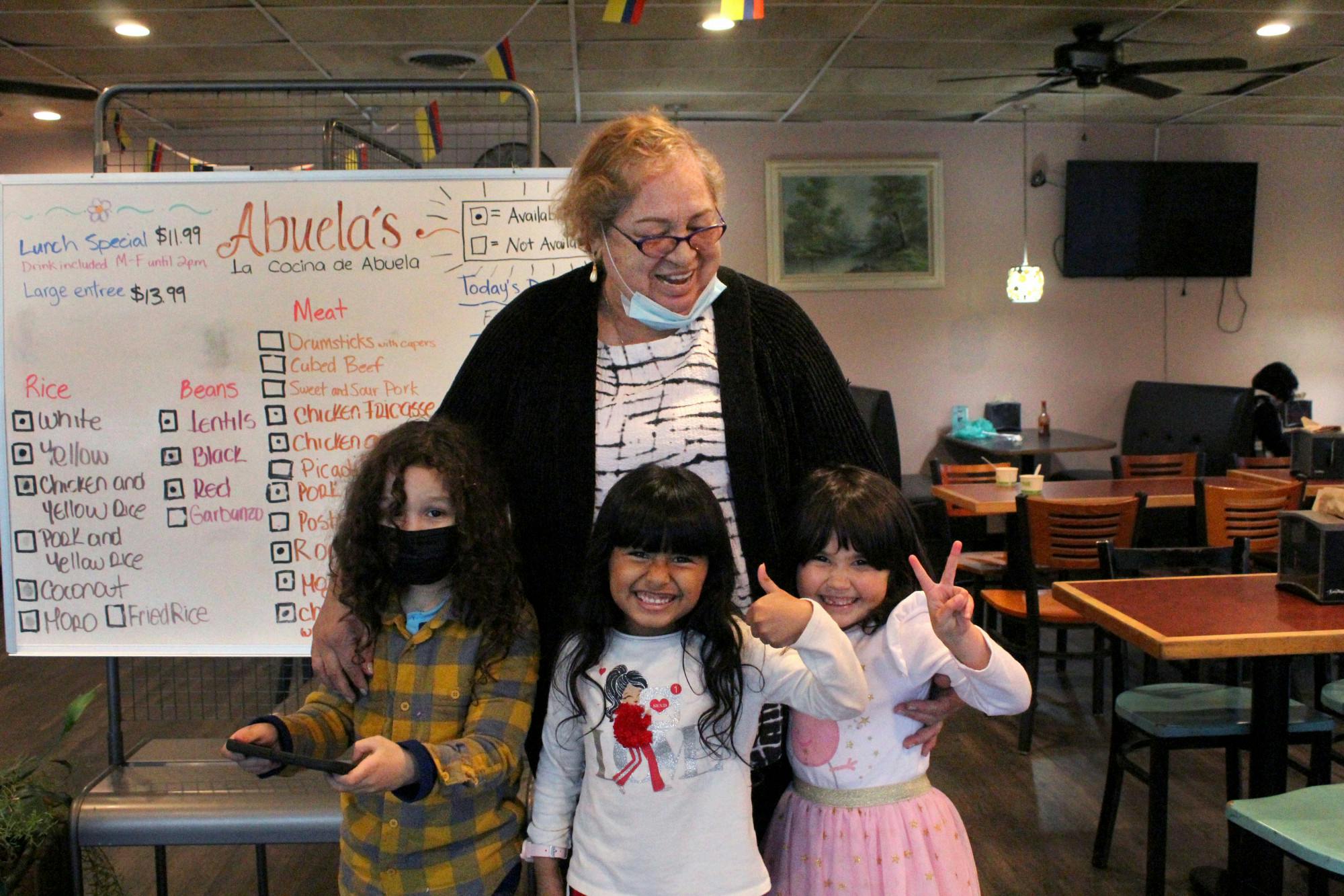 Marta Puyana, the namesake of La Cocina de Abuela, hugs her three grandchildren (left to right) Otis Puyana Darnell, 6, Valentina Peña Rey, 5, and Lucielena Puyana Darnell, 4, at La Cocina de Abuela on Friday, Jan. 21.