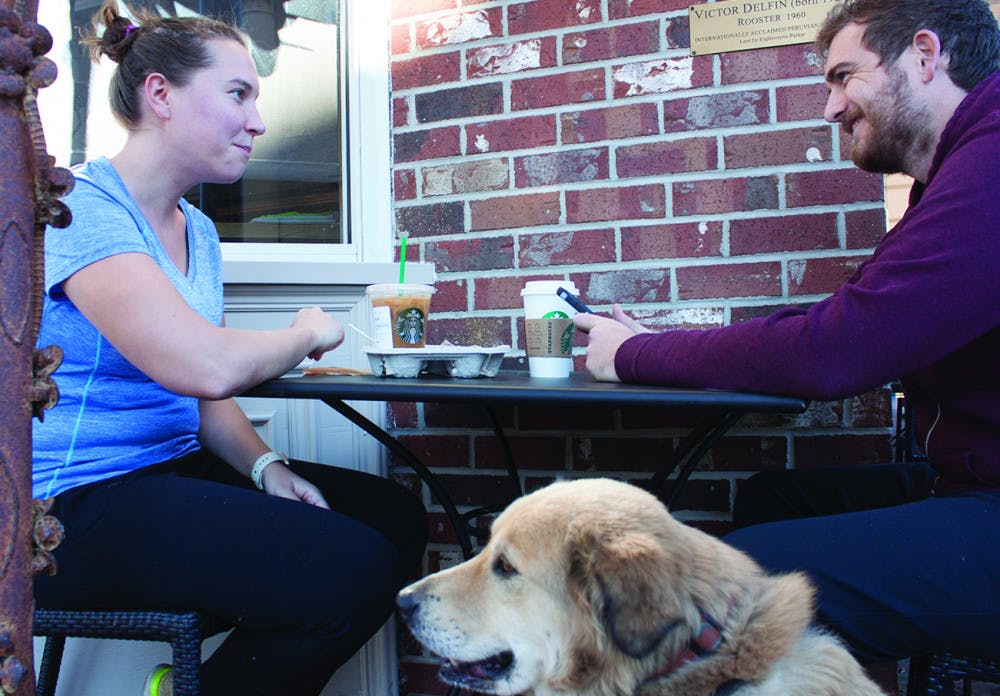 Carolyn Witman, an anesthesia resident at UF, eats and drinks coffee with Ryan Butler and his dog, Penny, outside of the downtown Starbucks, located at 201 SE First St., on Monday. After the Starbucks CEO pledged to hire 10,000 refugees, #BoycottStarbucks started trending on Twitter. “I’m anti-boycott and pro-Starbucks,” Witman said.