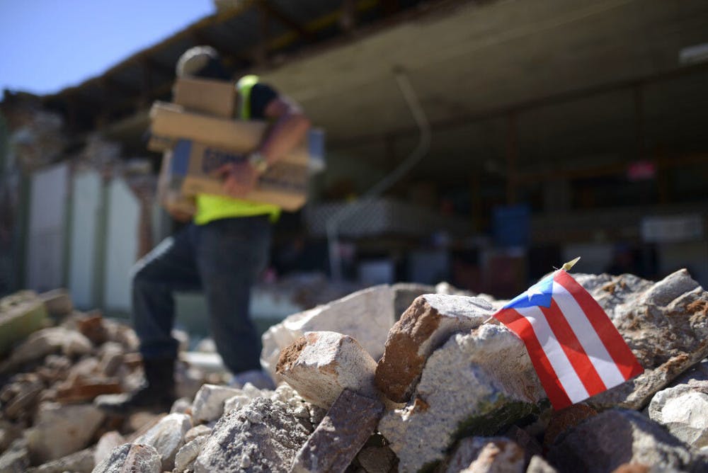 <p>A Puerto Rican flag hangs within the rubble, after it was placed there where store owners and family help remove supplies from Ely Mer Mar hardware store, which partially collapsed after an earthquake struck Guanica, Puerto Rico, Tuesday, Jan. 7, 2020. A 6.4-magnitude earthquake struck Puerto Rico before dawn on Tuesday, killing one man, injuring others and collapsing buildings in the southern part of the island. (AP Photo/Carlos Giusti)</p>