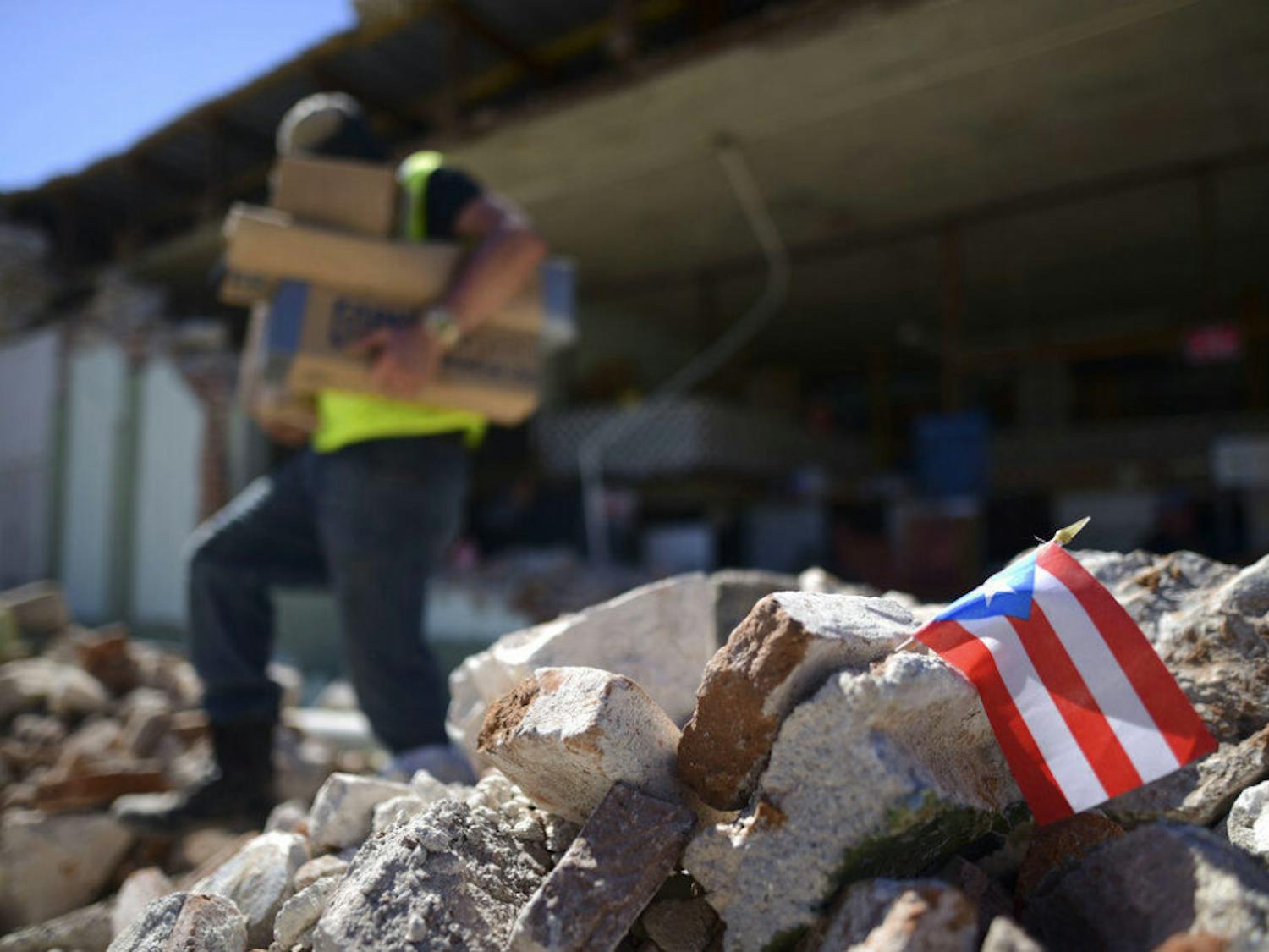 A Puerto Rican flag hangs within the rubble, after it was placed there where store owners and family help remove supplies from Ely Mer Mar hardware store, which partially collapsed after an earthquake struck Guanica, Puerto Rico, Tuesday, Jan. 7, 2020. A 6.4-magnitude earthquake struck Puerto Rico before dawn on Tuesday, killing one man, injuring others and collapsing buildings in the southern part of the island. (AP Photo/Carlos Giusti)