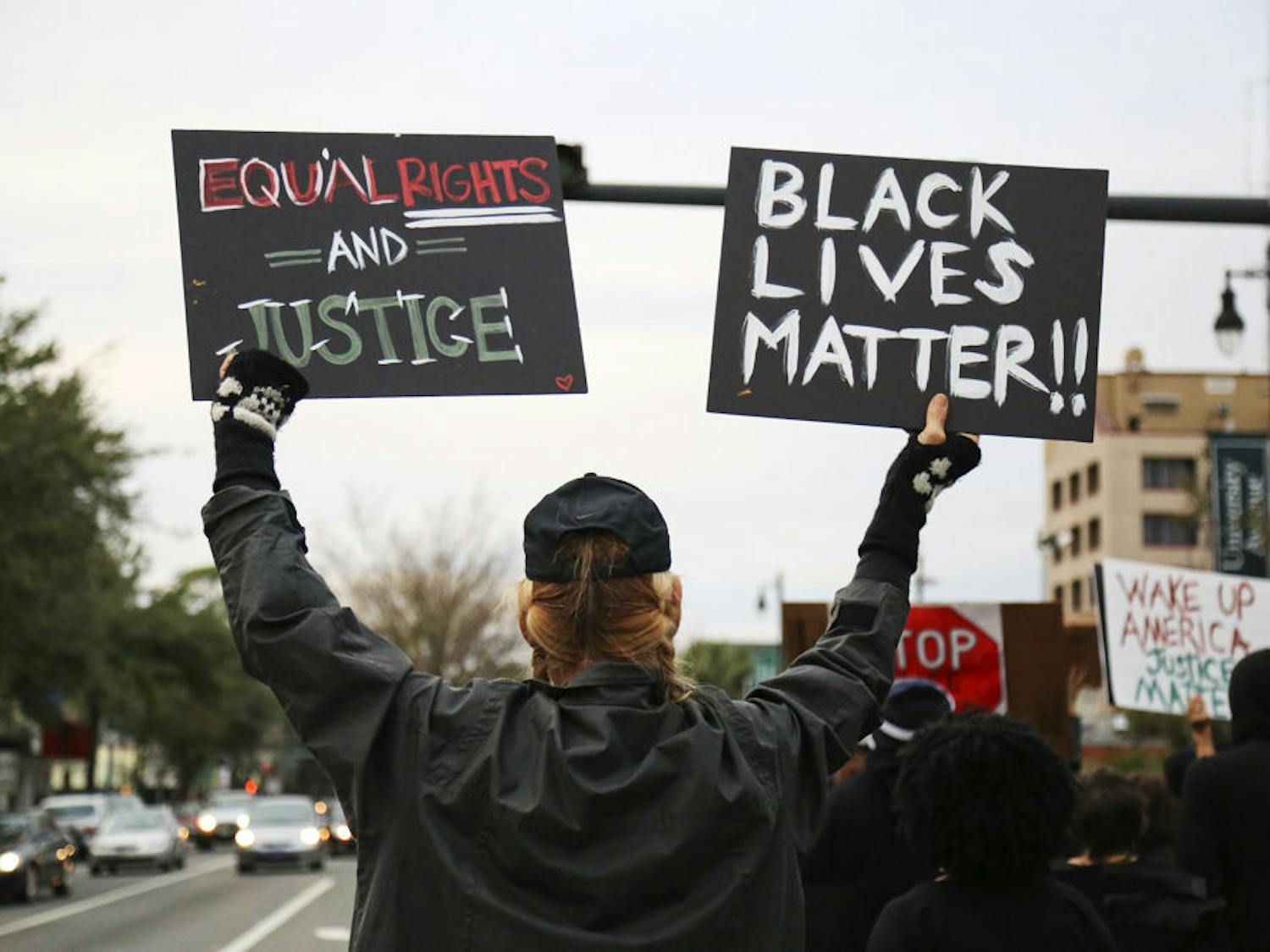 A protestor holds up signs during the #BLACKLIVESMATTER march on University Avenue Monday afternoon.