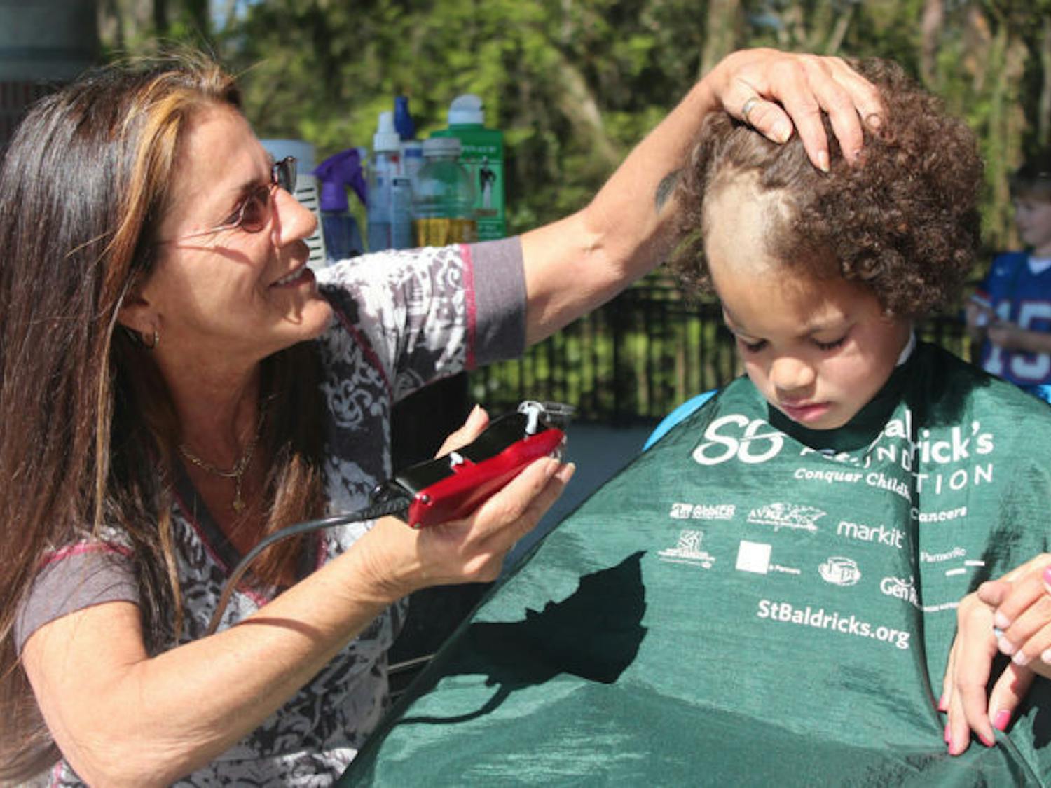 Marguerite Gaisser shaves Dwayne Lewis’ head Friday afternoon on Flavet Field as part of the Freshman Leadership Council’s annual St. Baldrick’s event benefiting cancer research. The 7-year-old, who is blind due to retinoblastoma, got his head shaved to celebrate being cancer-free for five years.
