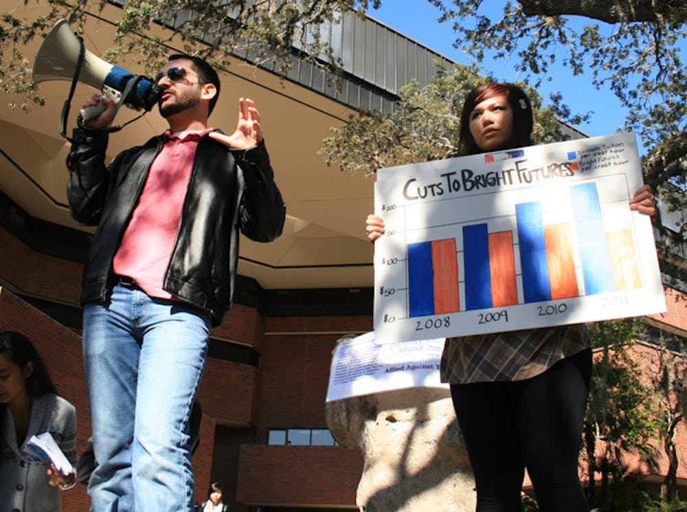 <p>Gator Student Alliance members Robbey Hayes, a 20-year-old anthropology junior, and Marie Dino, a 20-year-old education sophomore, educate UF students passing through Turlington Plaza on Wednesday afternoon about the cuts that the state is making in education and how it will affect future tuition.</p>