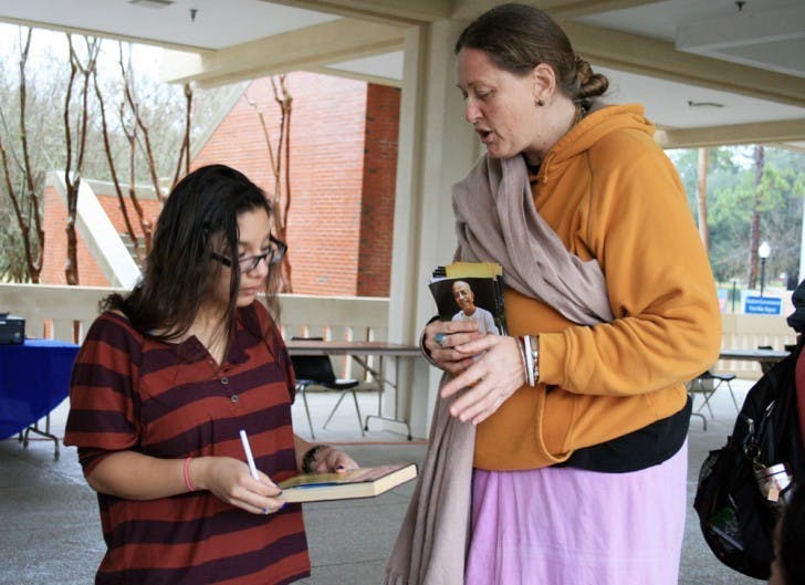 English freshman Debbie Vazquez, 18, asks Caitanya Long, who resides in the Krishna House, about Bhakti Yoga during the Religion Fair held on the Reitz Union Colonnade on Wednesday afternoon.