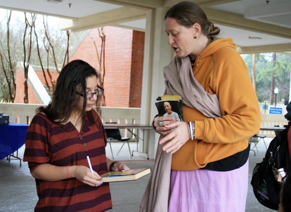 <p>English freshman Debbie Vazquez, 18, asks Caitanya Long, who resides in the Krishna House, about Bhakti Yoga during the Religion Fair held on the Reitz Union Colonnade on Wednesday afternoon.</p>