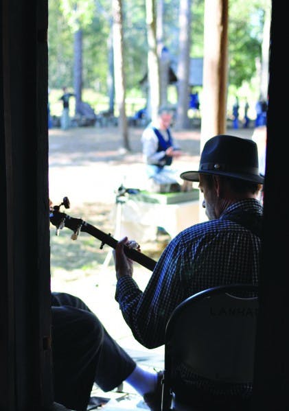 Bob Lanham strums a banjo on the porch of the farmhouse for passers-by. He was a member of a rotating cast of musicians who played throughout the day.