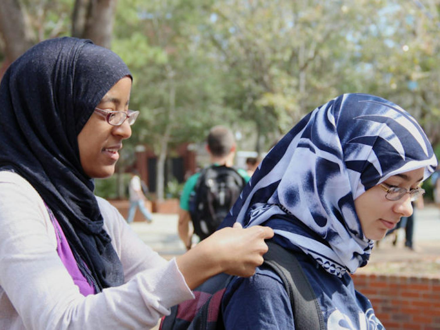Heiba Belal, 21, left, a UF microbiology senior, helps Lisdelys Garcia, 19, a UF biomedical engineering freshman, put on her hijab, a veil that covers the head, on Turlington Plaza on Monday for Islam on Campus’ “Hijab for a Day.”