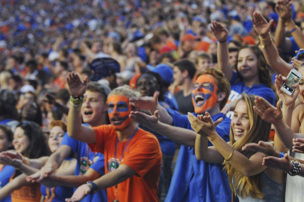 <p>Faces painted in orange and blue, Erik Teriele (left), a UF mechanical engineer freshman, and Chris Crary, a UF computer engineer freshman, perform the Gator Chomp during the Gators’ first game of the season. The 18-year-olds didn’t expect to get the seats that they were assigned. Teriele said they were freaking out when they realized how close they would be to the field.</p>