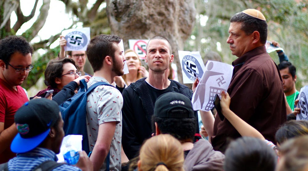 Students protest and stand in front of the man wearing a swastika on Thursday. 
