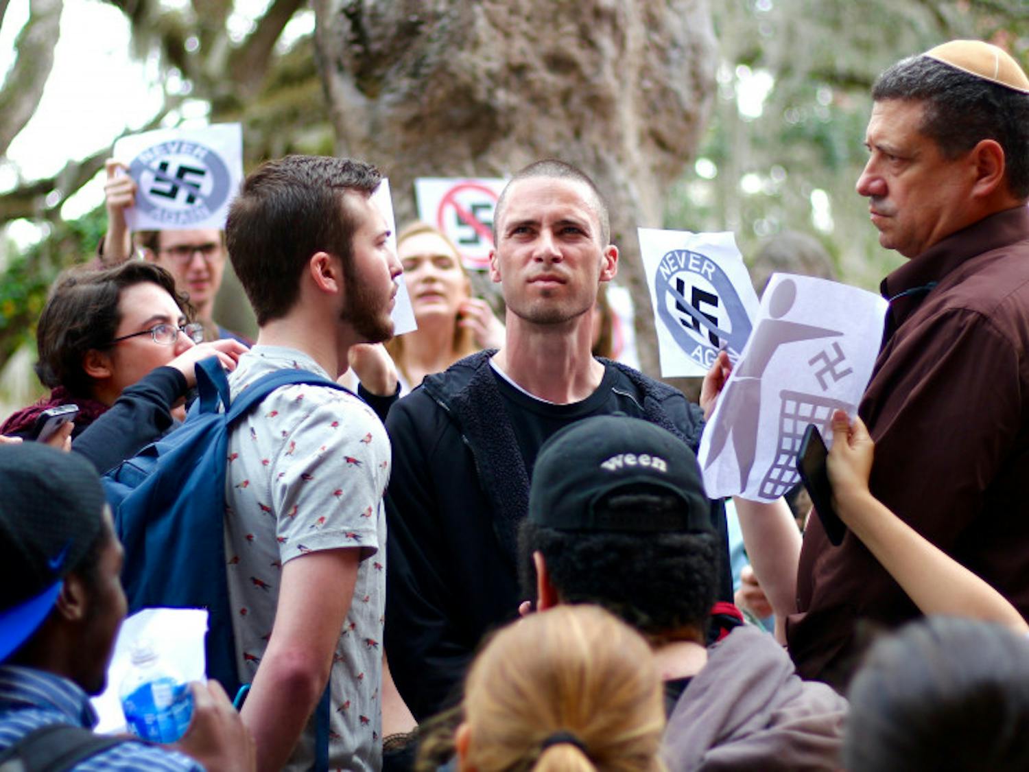 Students protest and stand in front of the man wearing a swastika on Thursday. 