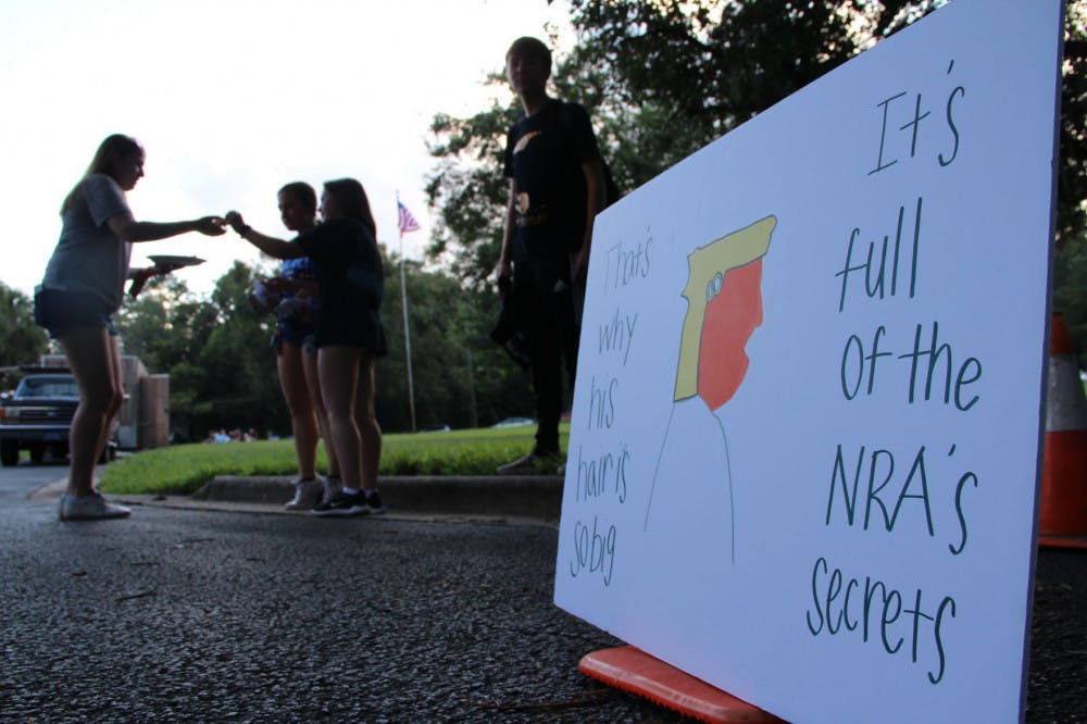 Madison Gore, an 18-year-old UF political science freshman, hangs with friends by her protest sign outside the Gainesville Woman's Club.