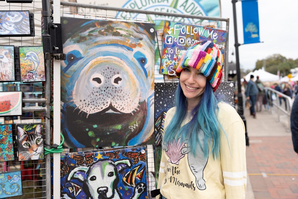Local animal artist, Samm Wehman, stands in front of her painting of a manatee at the Crystal River Manatee Festival on Jan. 14, 2024