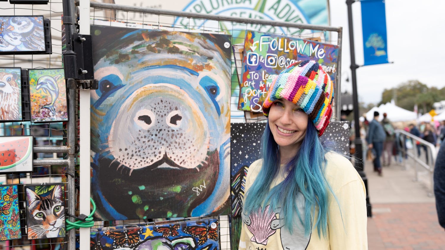 Local animal artist, Samm Wehman, stands in front of her painting of a manatee at the Crystal River Manatee Festival on Jan. 14, 2024