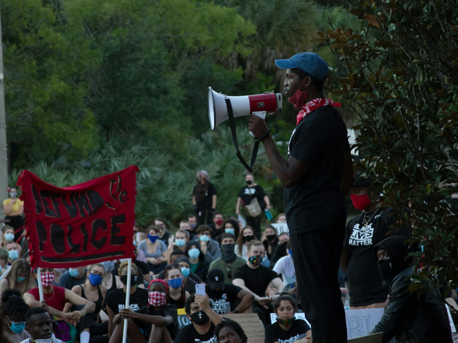 At a June 13 demonstration near the Gainesville Police Department, protesters chant "No justice, no peace," and a sign reading "Defund The Police" can be seen in the background. 