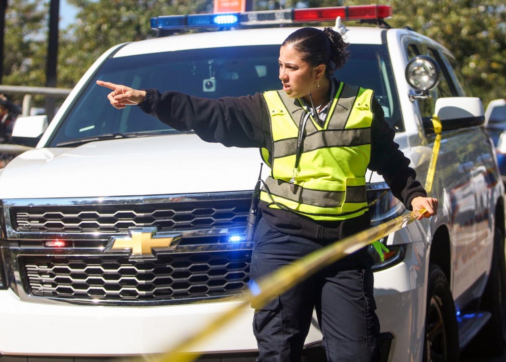 Christina Torres, 37, who works in the University Police training division, directs traffic on Center Drive on Wednesday morning after a bomb threat emerged from the New Engineering Building. According to an email UF sent to students on Wednesday, classes were canceled in that building for the remainder of the day to evaluate the credibility of the threat.