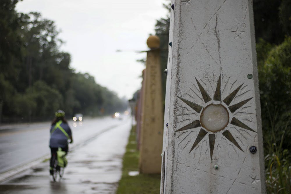 A biker passes by the statues Wednesday evening for Gainesville Solar Walk, a four billion to one scale model of the solar system located along NW 8th Avenue.