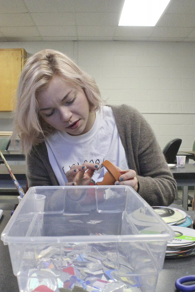 Marisa Panzarella, a 22-year-old UF advertising junior, glues CD shards to a gardening pot at a C.R.E.A.T.E. club meeting on Nov. 18, 2015, in McCarty A. Panzarella said she didn’t know what she wanted to make, but she showed up to have fun. Since Thanksgiving is next week, the event also included a potluck of apple pie, honey straws, cookies and macaroni and cheese.